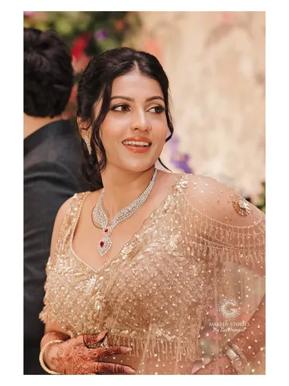 A candid shot of Shravya during her reception. Her makeup looks fresh and radiant, with a soft smokey eye and a natural lip color that allows her joyful expression to shine through.