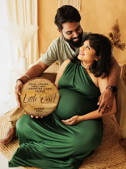 A creative announcement photo from a boho maternity session, with a wooden plaque counting down the days to their little one's arrival.