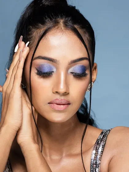 A serene beauty shot with eyes closed, highlighting the shimmery purple eyeshadow.