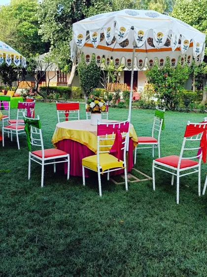 Colorful guest seating at an outdoor Mehendi, with multi-colored chair ties and a block-printed umbrella.