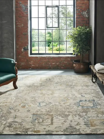This shot showcases a distressed-finish rug in a bright, industrial-style room. The large window and high ceilings provide a sense of scale, while the classic armchair adds a touch of contrasting elegance.