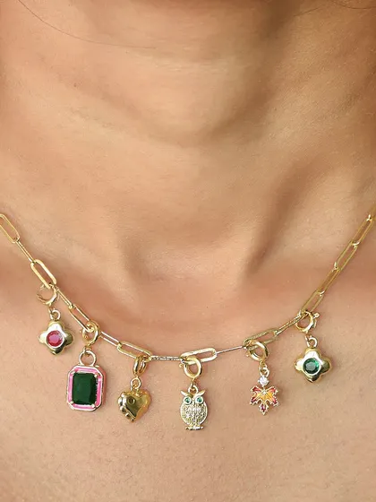 A custom charm necklace featuring a mix of colourful gems, a golden owl, and a heart charm. Each piece is chosen by you to create a unique story.