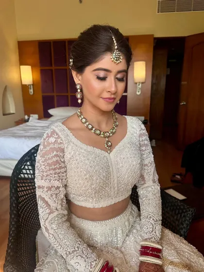 A close-up of a bride's serene expression, her hair styled in a neat, traditional bun. This look is perfect for a daytime wedding, offering a fresh and timeless feel.