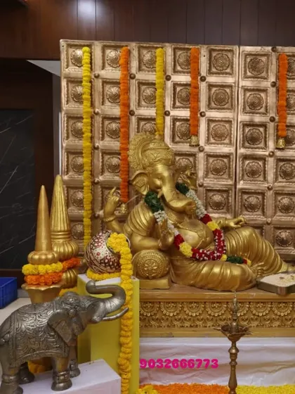 Another Ganesha installation, this time set against a golden textured backdrop with hanging marigold garlands.