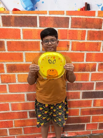 A proud student shows off his completed giraffe painting. Seeing their ideas come to life is a huge confidence booster for our young artists.