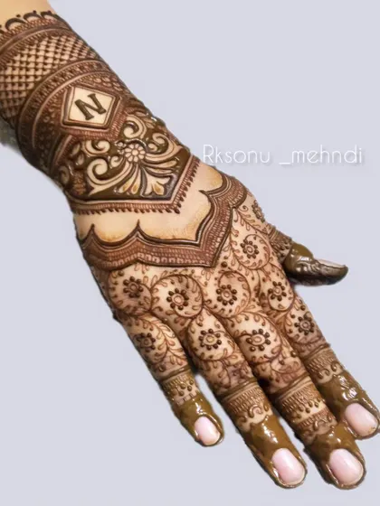 An elegant design featuring a personalized initial 'N' within a decorative frame. The palm is covered in a beautiful pattern of repeating floral circles, creating a delicate and feminine look.