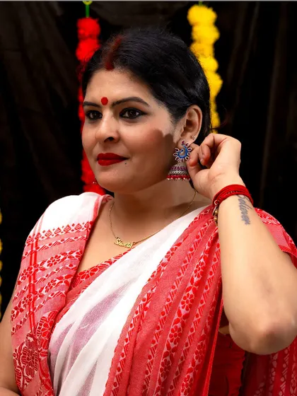 A classic portrait in a red and white saree, perfect for Durga Pooja. The blue jhumkas add an unexpected pop of color.