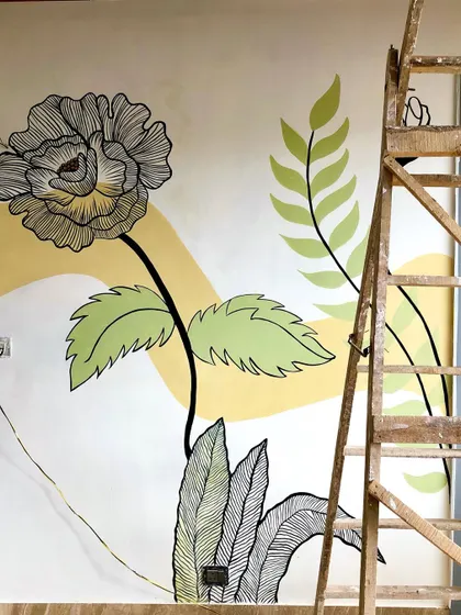 A process shot of the large floral mural, showing how the design is sketched out on the wall before the color and details are added.