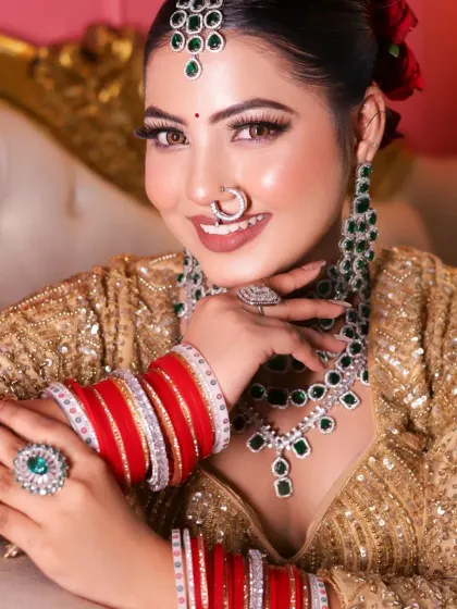 A stunning bridal look with a golden lehenga and emerald jewelry, created by a student.