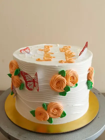 A simple white cake decorated with orange buttercream rosettes and butterfly toppers.
