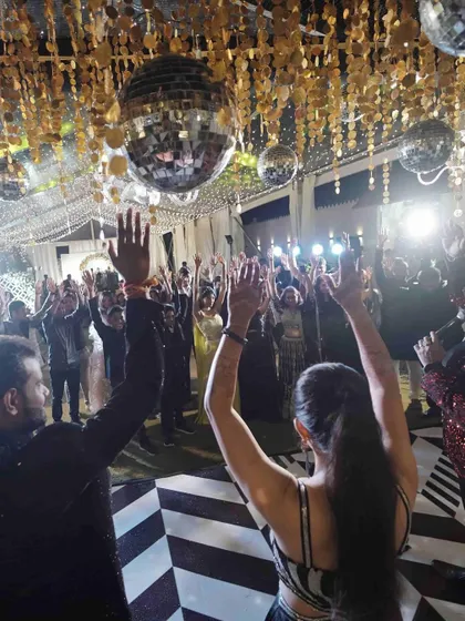 Getting the whole crowd to put their hands up. This shot captures the collective energy of a successful Sangeet night where everyone is vibing together.