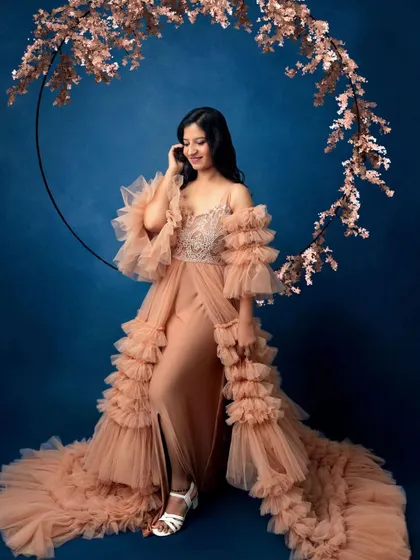 A portrait of a mother-to-be looking like a goddess. The flowing gown and floral hoop create a dreamy, ethereal atmosphere, celebrating the magic of creating life.