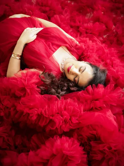 A duplicate of image 112, this artistic overhead shot captures the mom-to-be resting in a beautiful sea of red tulle.