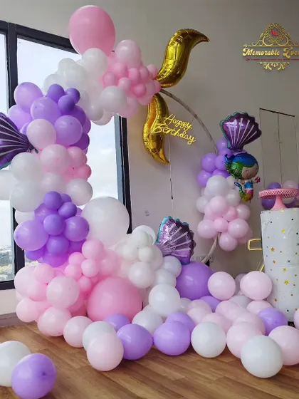 An imaginative mermaid-themed birthday decoration with a balloon arrangement that mimics underwater bubbles and a golden mermaid tail.