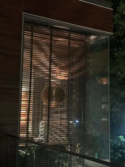 A closer night-time detail of the T House study. The reflection on the glass merges the interior with the surrounding trees, blurring the boundary between the built space and the natural environment.
