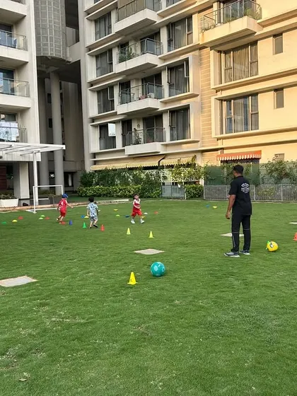 A coach guides our youngest players through drills on a lush green lawn, making learning feel like playtime.