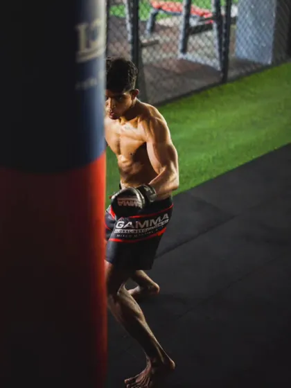 A fighter focused on his target. This shot captures one of our athletes mid-strike on a heavy bag, showcasing his defined physique and concentration.