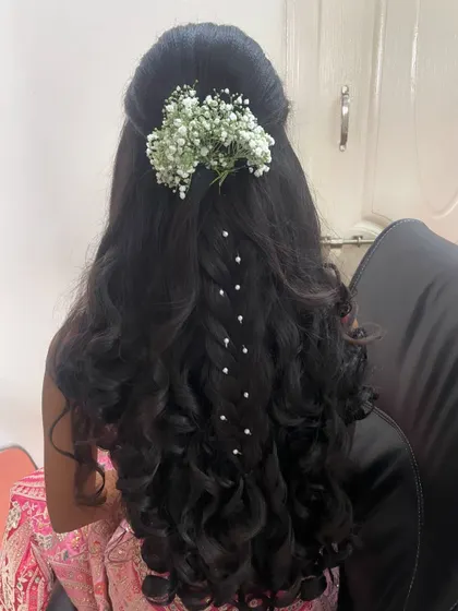 A pretty and youthful hairstyle for a party. This half-up style features a delicate braid with pearl accents and voluminous curls.