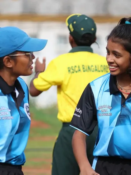 Two teammates discuss strategy between overs during a Dasara Cup game.