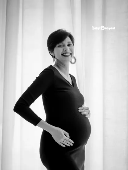 The happiness of waiting for your little one. This black and white photo captures a simple, joyful moment of a mother-to-be holding her bump.