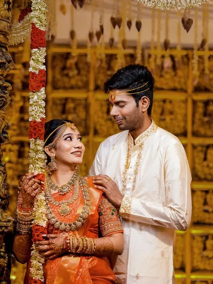 A candid moment on the wedding stage, capturing the couple's interaction against the stunning temple-themed decor.