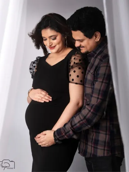 A loving embrace from her partner. This portrait beautifully showcases their connection against a simple, clean backdrop.