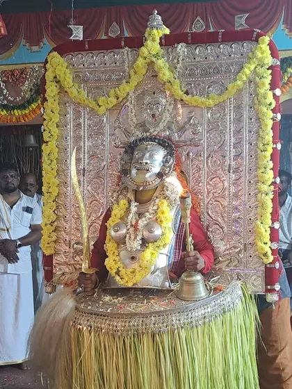 Another view of the Dhumavati daiva, showcasing the impressive silver ornamentation and the skirt made of green areca leaves.