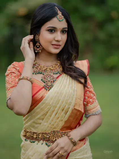A beautiful model showcasing a layered antique necklace set with red and green kemp stones. This is a versatile set that can be worn for weddings or other grand celebrations.