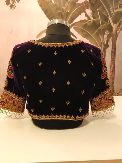 The back view of the royal purple velvet blouse, showing the elegant embroidery pattern and the rich texture of the fabric. We look for pieces that are beautiful from every angle.