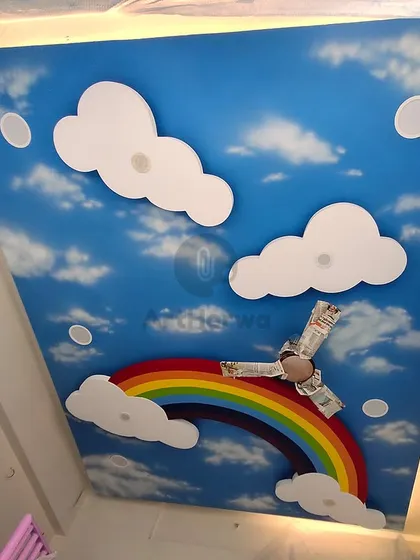 We transformed this kid's room ceiling into a bright blue sky with a rainbow and fluffy 3D clouds. This immersive design makes the room feel magical and fun.
