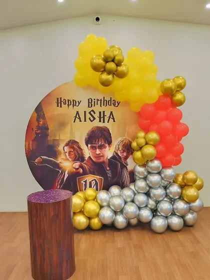 A closer look at the Harry Potter backdrop and balloon arrangement. The gold, red, and silver balloons complement the movie poster design for a magical effect.