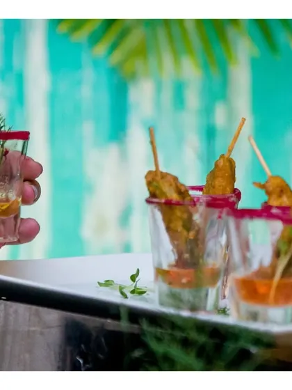 Chicken satay skewers served in shot glasses with a peanut dipping sauce, a classic Asian appetizer presented with a modern twist.
