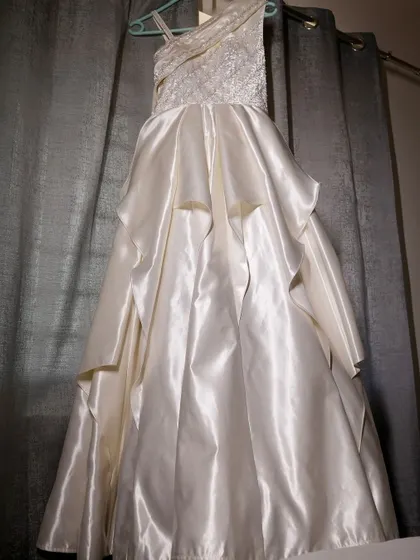 A detailed look at the craftsmanship of a custom wedding gown, showing the textured fabric of the bodice and the elegant drape of the satin skirt.