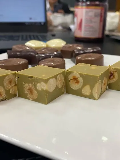 A close-up of our pistachio and hazelnut gianduja squares. We make these by blending finely ground roasted nuts directly into the chocolate, creating a confection that is incredibly smooth and rich in authentic nut flavor.