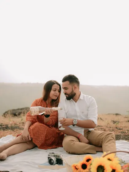 A celebratory moment with champagne during a picnic-style pre-wedding shoot, marking the beginning of their new chapter.