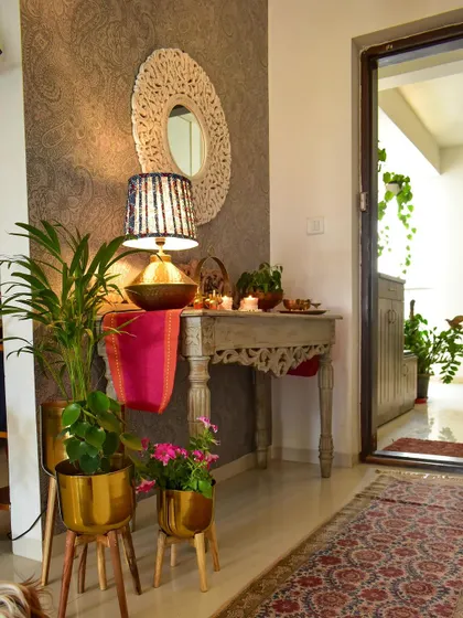 A daytime view of my foyer, with a colorful runner and plants in brass planters. The natural light makes the space feel so airy.