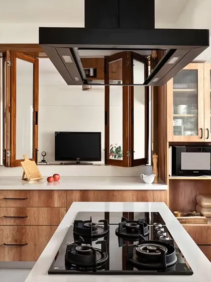 The fully renovated 'Rooted Japandi Home' kitchen, now the heart of the home. We installed an island with a hob, custom teak laminate cabinetry, and a bifold window that opens to the family lounge, ensuring the space is both functional for cooking and connected to family life.
