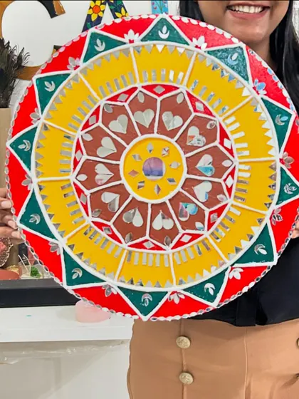 A very colorful and festive Lippan art creation, with bright yellow, red, and green, and heart-shaped mirrors.
