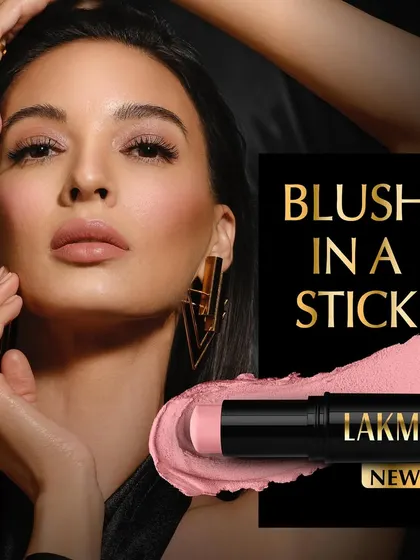 A commercial shot for Lakmé's 'Blush in a Stick'. The model's soft, rosy cheeks are the focus, demonstrating the product's natural-looking color payoff. The stick format and a swatch are shown for complete product information.