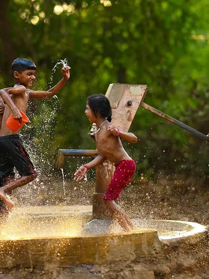 The golden light of the evening sun illuminates the water splashing around the children. This shot highlights the beautiful atmosphere surrounding their energetic play.