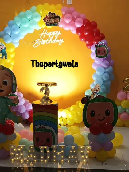 A Cocomelon theme with a bright yellow backdrop and a rainbow balloon ring.
