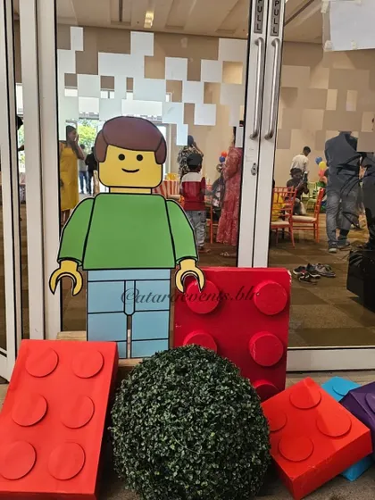 A life-sized LEGO man cutout and giant red LEGO bricks stand at the entrance, welcoming guests to the building-themed celebration.