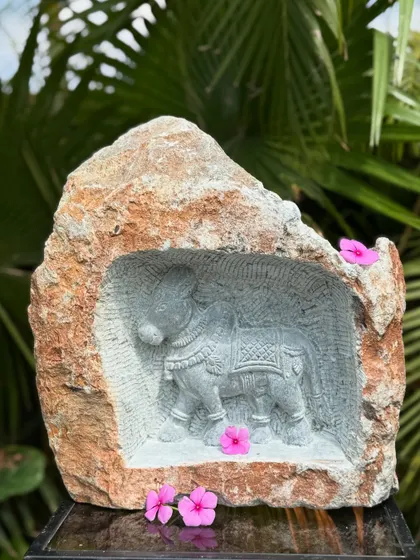 A natural rock carving of a caparisoned elephant, inspired by South Indian temple art. The intricate sculpture, set within the raw stone, adds a touch of spirituality and artistry to your garden.