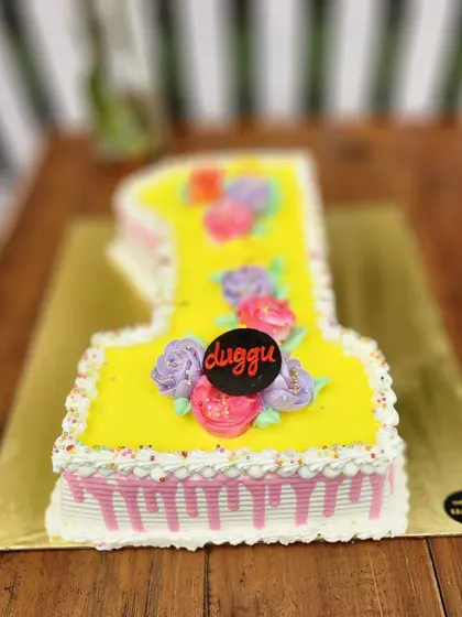 A bright yellow number "1" cake decorated with colorful buttercream flowers. A cheerful and delicious way to celebrate a first birthday.