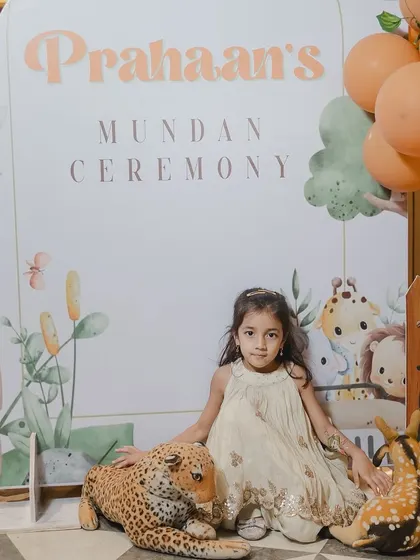 A cute guest posing with the jungle-themed props at the Mundan ceremony.