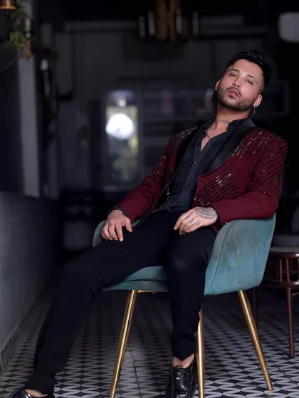 This client relaxes in style, wearing our maroon sequin tuxedo. It's a versatile piece that looks great whether you're standing or sitting.