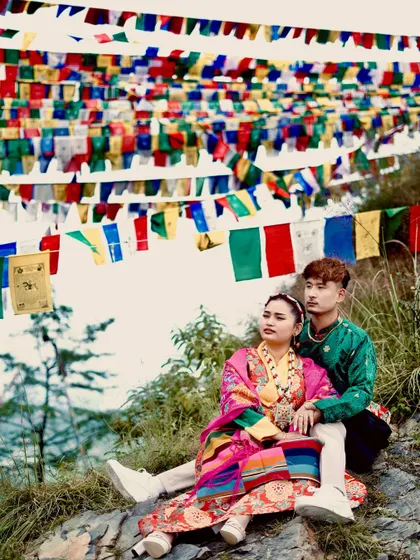 A couple's portrait celebrating traditional Kinnauri attire against a backdrop of vibrant Buddhist prayer flags. This kind of cultural photoshoot is special to me and highlights the rich heritage of Himachal.