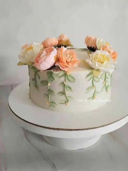 A beautiful floral birthday cake made with zero fondant. The design features a crown of delicate flowers and hand-piped green vines for a fresh, garden-inspired look.