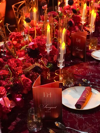 A close-up of the tablescape from the Sangeet night. Personalized menus, rich red floral centerpieces, and elegant candlelight contributed to the opulent and dramatic theme.