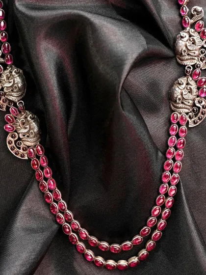 A different perspective of the red stone and silver peacock necklace, showing how the multiple strands drape elegantly.